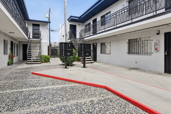 Charming courtyard view of a modern apartment complex with stylish railing and convenient mailbox access.