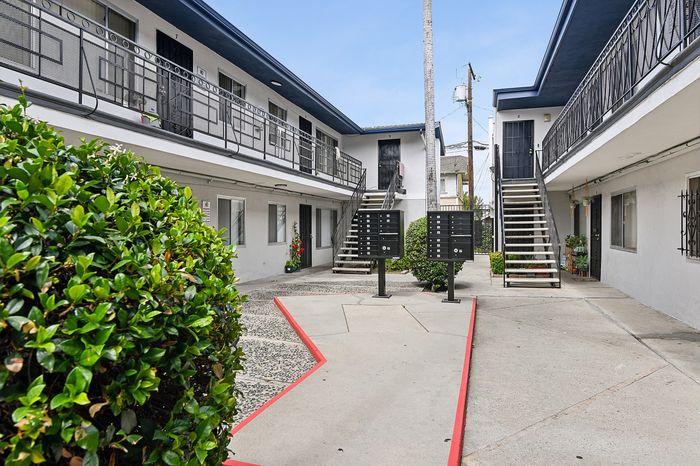 Charming apartment complex courtyard featuring modern architecture, lush greenery, and convenient mailboxes.