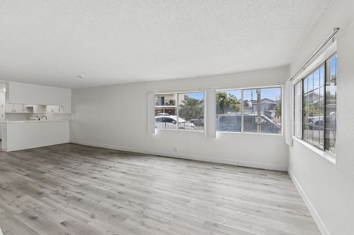 Bright and spacious living area with large windows, open floor plan, and stylish hardwood flooring.
