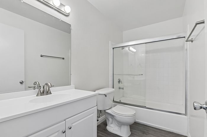 Bright and modern bathroom with sleek vanity, large mirror, and glass-enclosed shower.