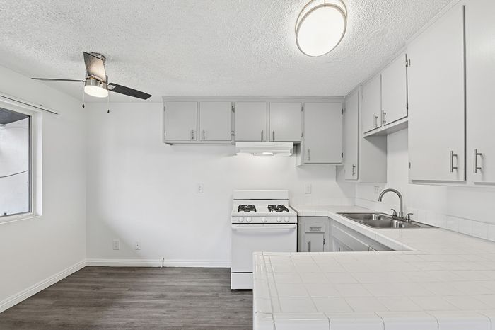 Bright and airy kitchen featuring modern white cabinetry, sleek countertops, and stainless steel fixtures, perfect for culinary creativity.