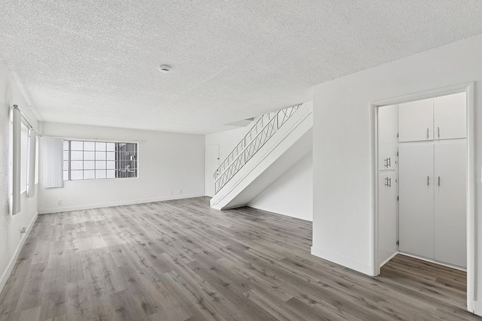 Sleek and modern open living space with elegant staircase, large windows, and stylish wood flooring, perfect for a bright and airy atmosphere.