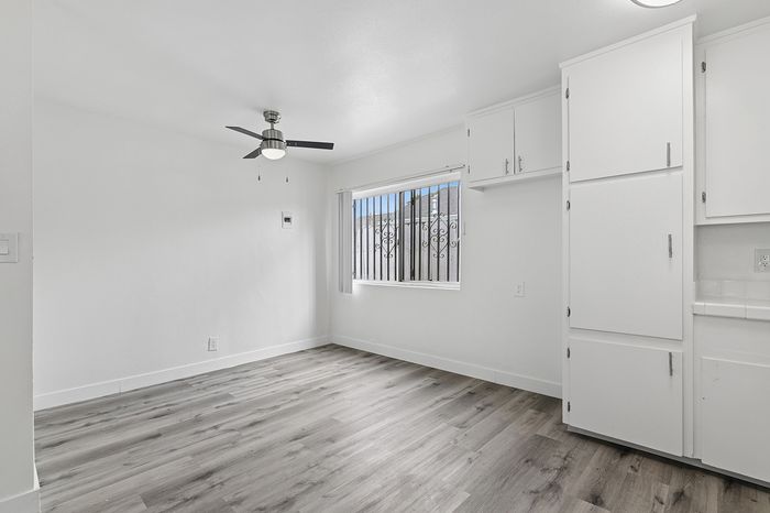 Bright, modern living space featuring sleek hardwood floors, a ceiling fan, and ample natural light from large windows.