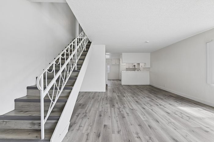 Modern open-concept interior with sleek stairs, expansive living area, and minimalist kitchen design.