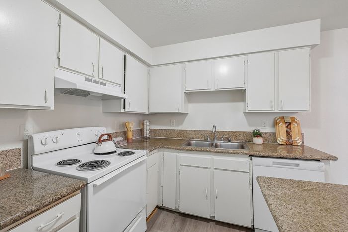Inviting kitchen with sleek white cabinetry and modern appliances, featuring a cozy countertop space for easy meal preparation.