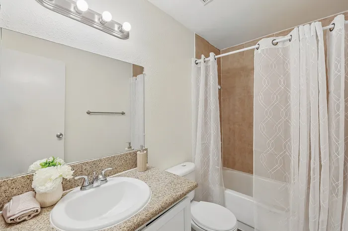 Bright and modern bathroom with elegant granite countertop, white sink, and stylish shower curtain.