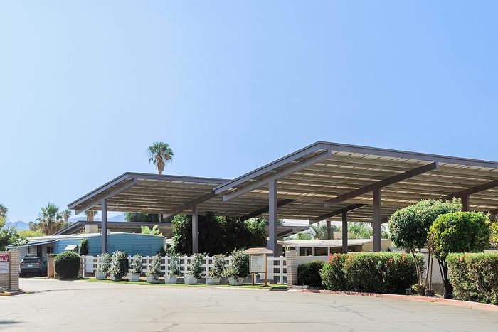 Spacious parking area with modern carports surrounded by lush greenery and clear blue sky.