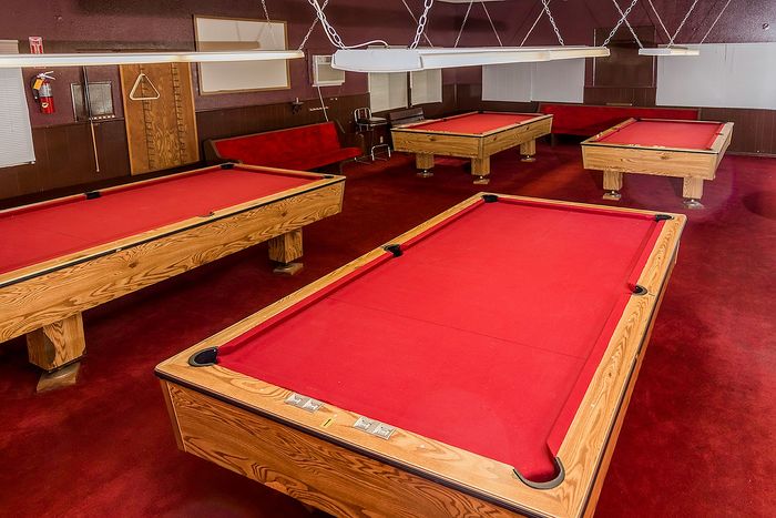 Inviting recreation room with multiple billiards tables featuring striking red felt, perfect for a lively game night.