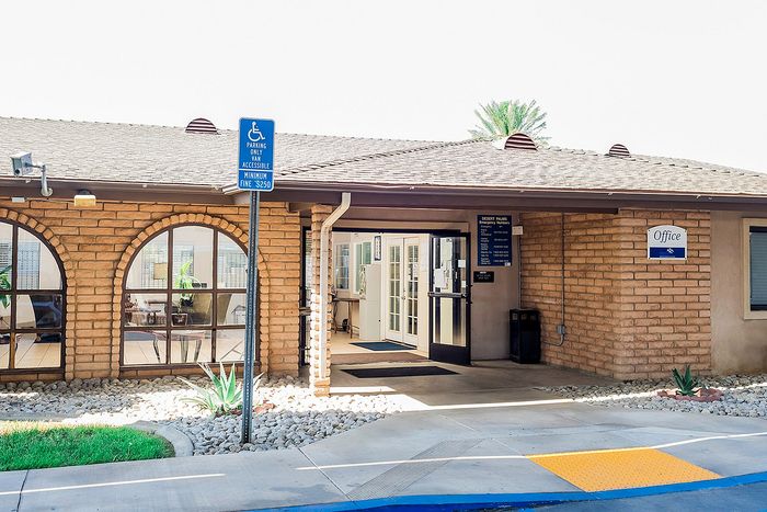 Inviting office entrance with charming brick design, arched windows, and welcoming pathway surrounded by greenery.