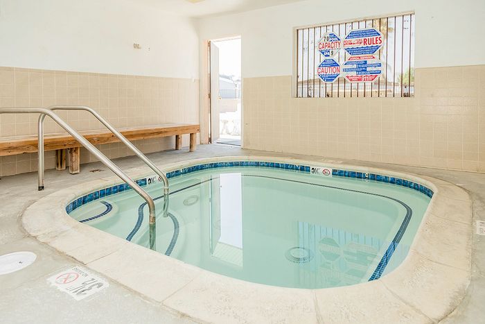 Inviting indoor spa room featuring a cozy whirlpool with modern tile finishes, perfect for relaxation and rejuvenation.