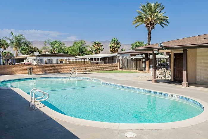 Inviting outdoor pool area with palm trees and a scenic mountain backdrop, perfect for relaxation and leisure.