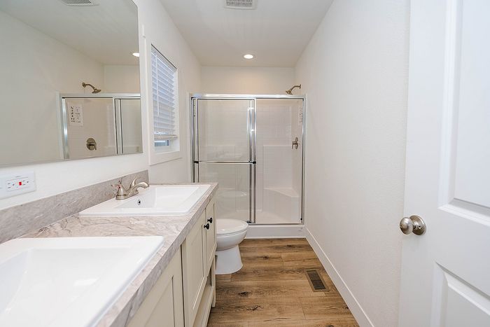 Elegant bathroom with dual sinks, sleek countertops, and a modern glass shower in a bright, welcoming space.