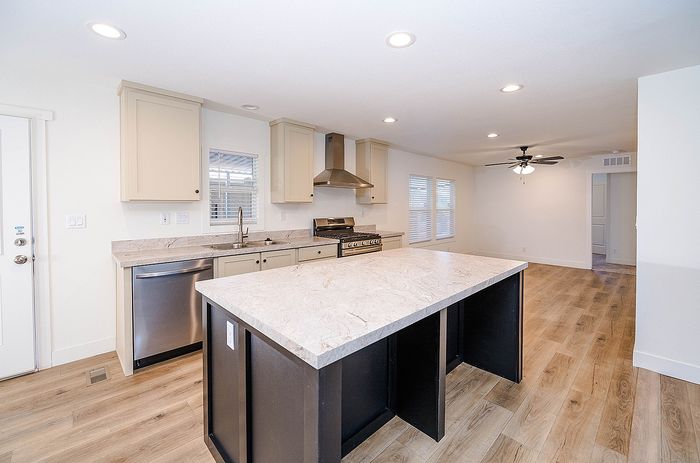 Modern open-concept kitchen with elegant marble island, stainless steel appliances, and inviting hardwood floors, perfect for entertaining.