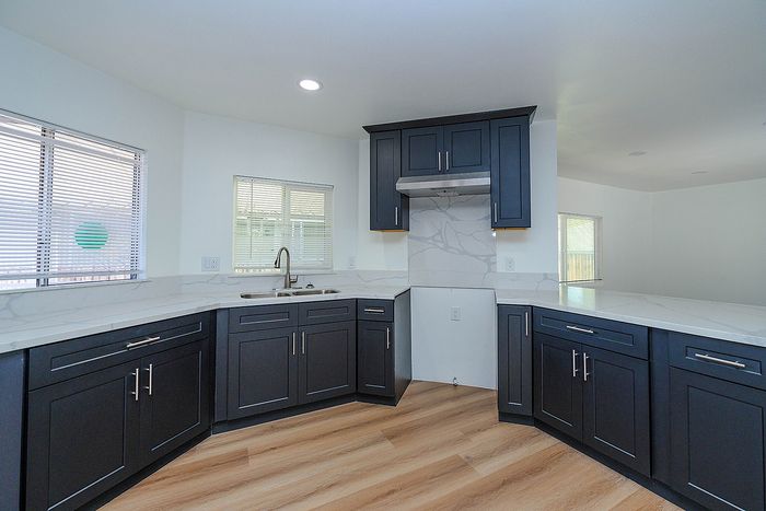 Bright, contemporary kitchen featuring sleek dark cabinets, elegant marble countertops, and modern fixtures with abundant natural light.