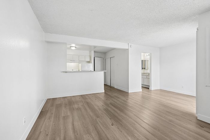 Spacious open-plan living area with sleek wooden floors, modern kitchen space, and ample natural light.