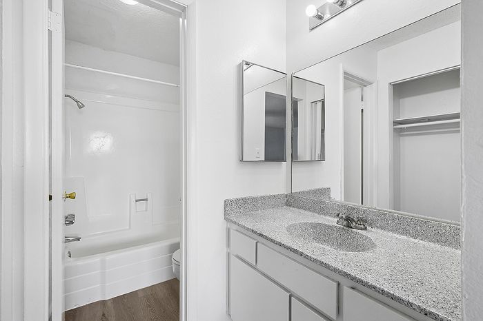 Chic bathroom featuring a modern vanity with granite countertop, spacious mirror, and elegant shower-tub combo.