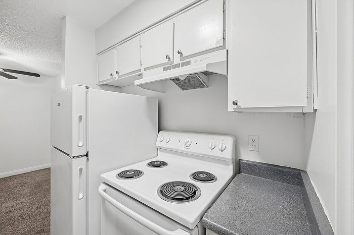 Modern and cozy kitchen with sleek white appliances, ample cabinetry, and a spacious countertop, perfect for cooking enthusiasts.