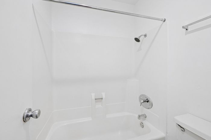 Sleek and modern bathroom featuring a pristine white bathtub with elegant chrome fixtures.