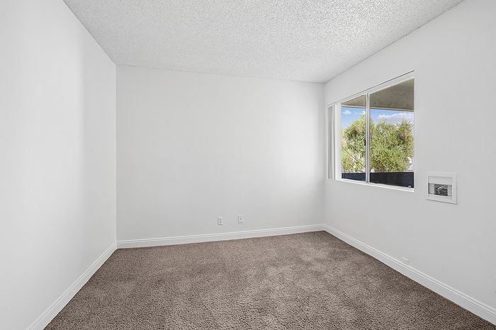 Bright, inviting room with plush carpet, large window offering natural light and scenic views.