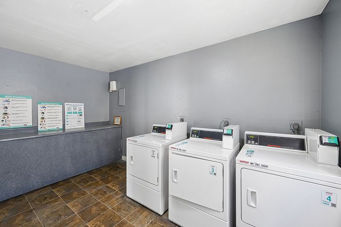 Modern laundry room featuring state-of-the-art washers and dryers, complete with user-friendly instructions and tiled flooring.