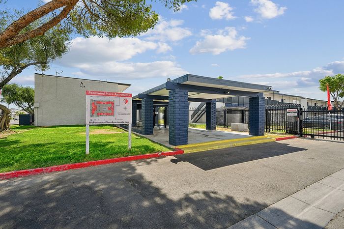 Modern Pennwood Place Apartments entrance featuring a sleek design, lush green surroundings, and ample parking space.
