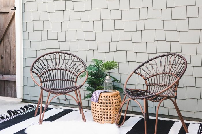 Patio chairs, a potted plant, a table all staged around a relaxing outdoor backyard setting.