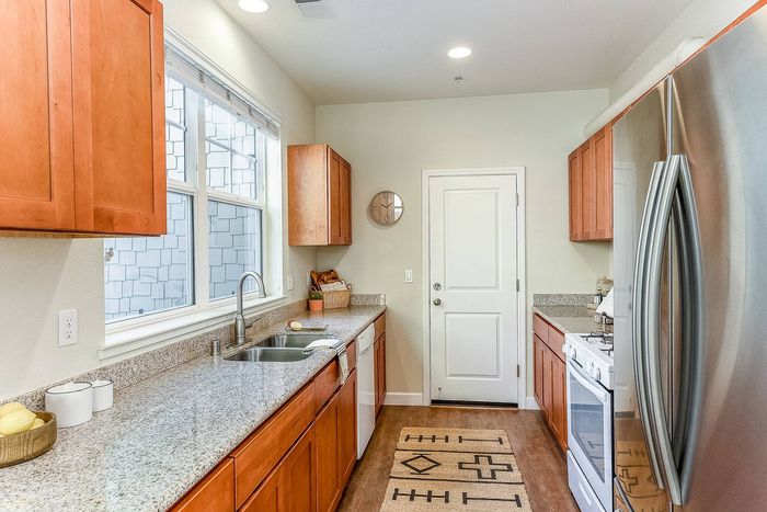Galley kitchen with large dual windows framing the sink, a gooseneck faucet and gas range.