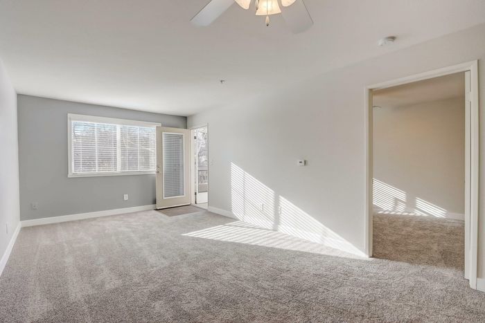 large open living spaces with plush carpeting and ceiling fan