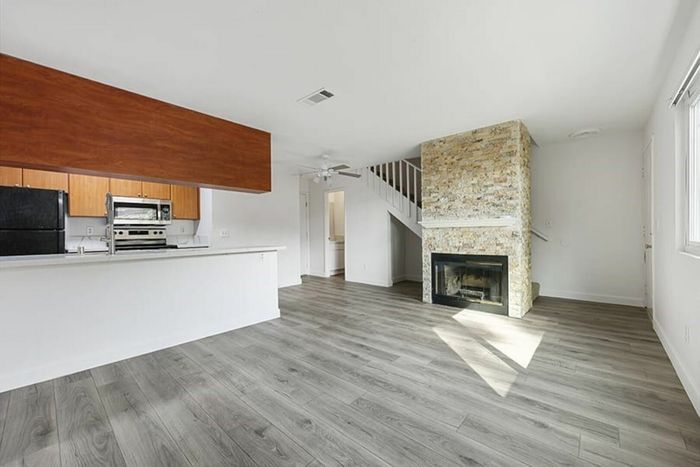 living room with a fireplace and kitchen with vinyl wood like flooring and stainless steel appliances