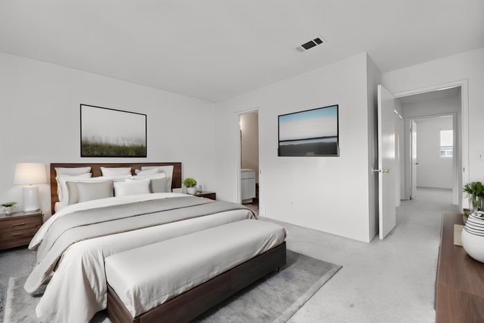 rendering of a furnished bedroom with large bed and dresser and access to master bathroom