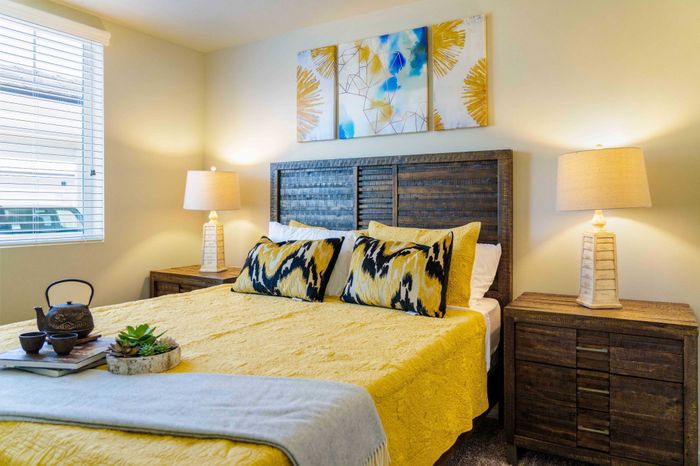 bedroom with nightstands and bed with yellow comforter and pillows at Turtle Creek apartments