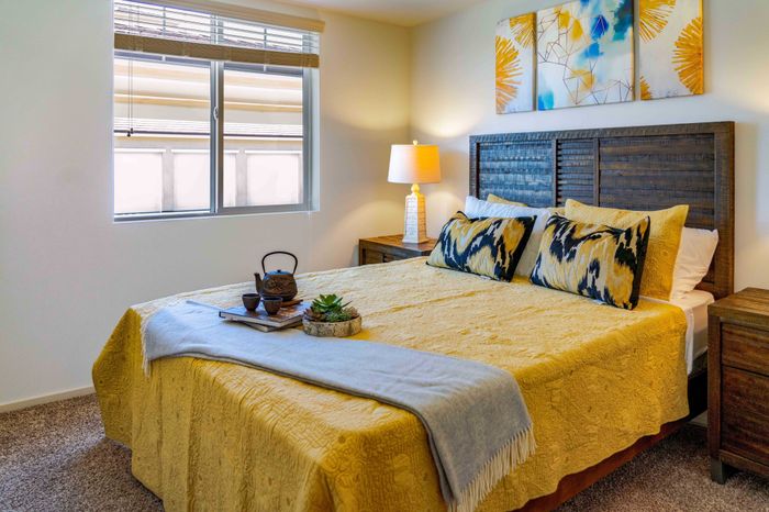 bedroom with nightstands and bed with yellow comforter and pillows at Turtle Creek apartments