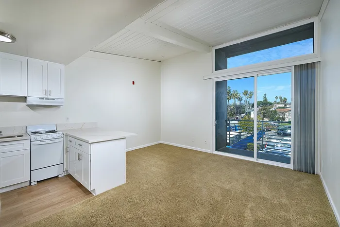 Kitchen with breakfast bar and living room leading out to balcony