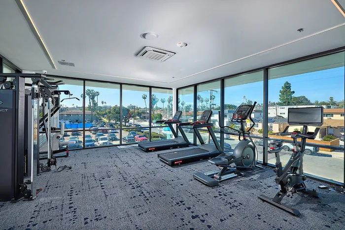 Renovated Fitness center at Cedar Shores featuring floor to ceiling windows, treadmills, ellipticals, stationary bike, and various weight machines