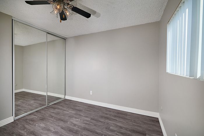 Spacious bedroom with ceiling fan, mirrored closet doors