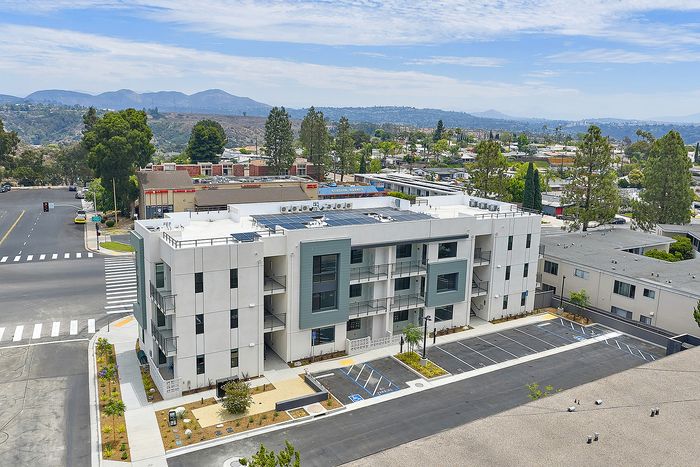 Serra Mesa, San Diego, CA Apartments with In-Washer and Dryer - DEZI - Aerial View of the Apartment Building with Resident Parking, Rooftop Solar Panels, Sidewalk, Street, and Natural Views Around the Community.