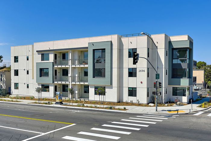 Apartments in Serra Mesa, San Diego, CA, with In-Washer and Dryer - DEZI - Street View of Apartment Building with Sidewalk, Street Lamp, Traffic Light, and Pedestrian Crossing.
