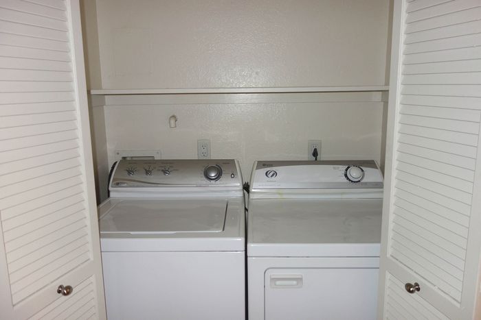 In-home laundry closet featuring a side-by-side washer and dryer set behind white louvered doors.