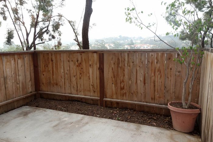 A private outdoor patio enclosed by a wooden fence, offering space for a container garden or outdoor seating.