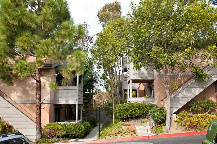Multi-story apartment buildings tucked into lush, mature green landscaping.