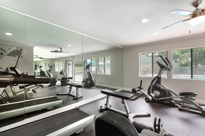 Bright fitness center featuring cardio machines and wall-to-wall mirrors.
