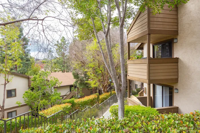 Apartment building exteriors with private balconies overlooking green space.