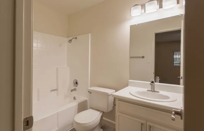 Bathroom featuring a white vanity with upgraded counters and a tub-shower.