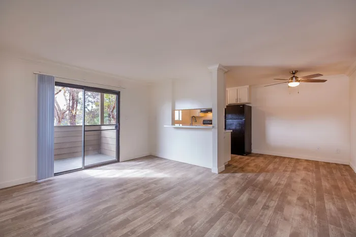 Wide-angle view of the living and dining space with upgraded flooring and balcony access.