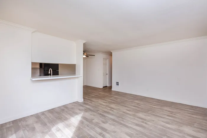Living area with wood-style plank flooring and a view into the kitchen.