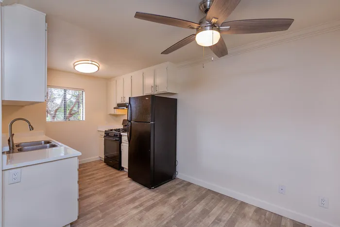 Kitchen area featuring black appliances, white countertops, and a dining area ceiling fan.