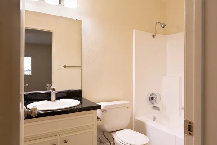 Clean bathroom with a large vanity mirror and white shower-tub combo.