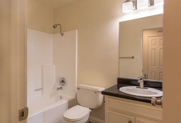 Clean bathroom with a large vanity mirror and white shower-tub combo.