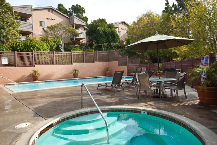 Refreshing swimming pool and spa area with outdoor dining tables and umbrellas.