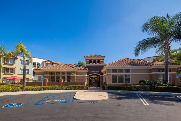 Exterior view of the Elan Pacifico community clubhouse and leasing office under a clear blue sky.